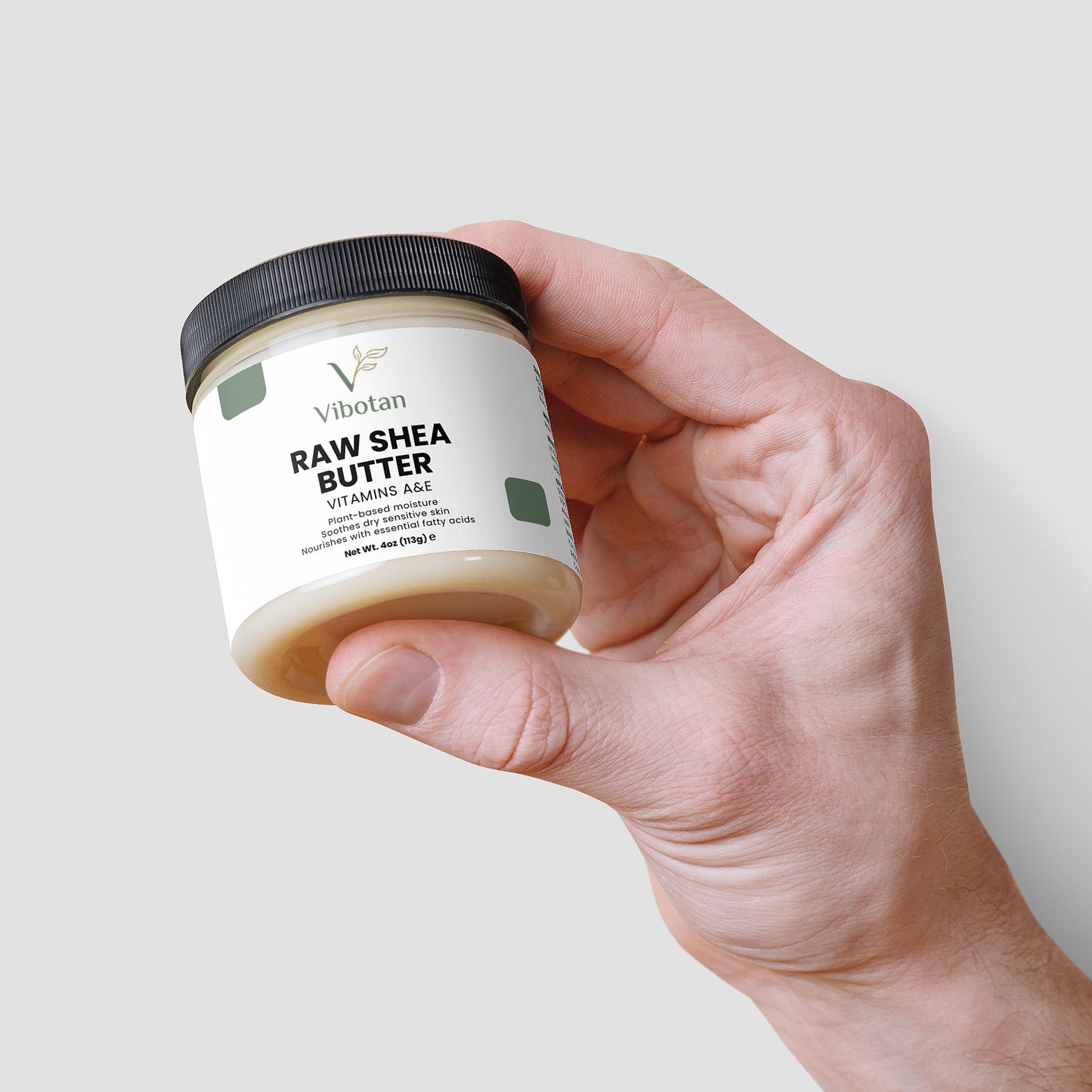 Hand holding a jar of Vibotan Raw Shea Butter against a light background